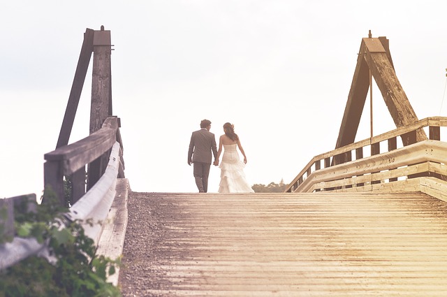 manželé jdou po dřevěném mostě, jsou na odchodu v dáli a obráceni zády